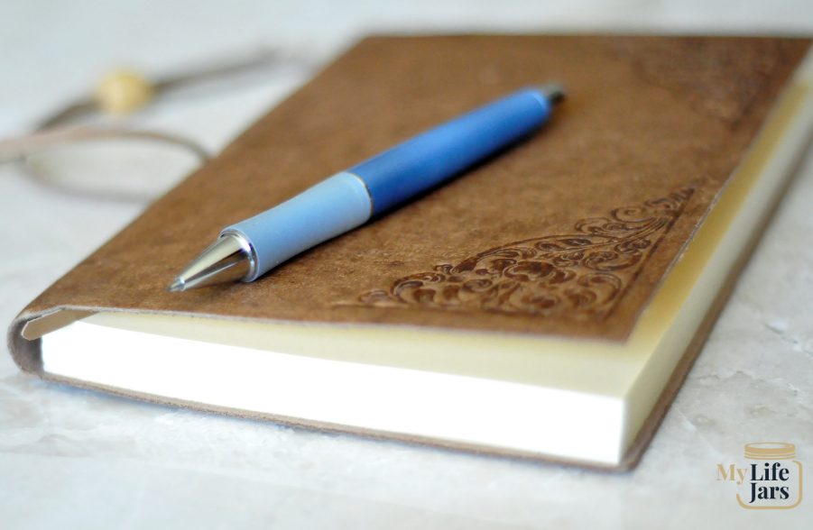 a brown journal with a blue pen getting ready to learn how to write
